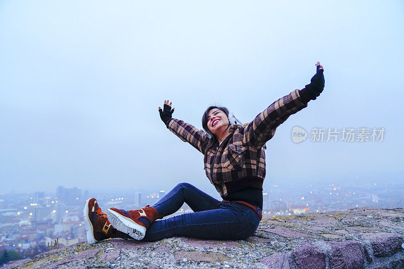 享受年轻的模特在冬天的衣服有乐趣在一个阴天外面。梦中女子在冬城有节日的心情。