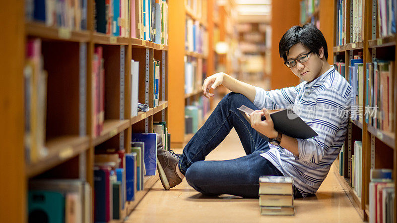 聪明的亚洲人学生在图书馆看书