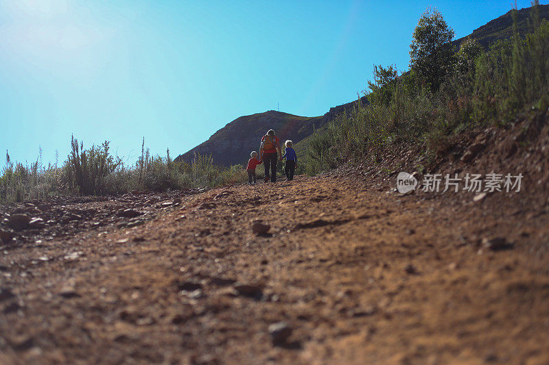 一个单身妈妈带着她的孩子们走在陡峭的岩石路上