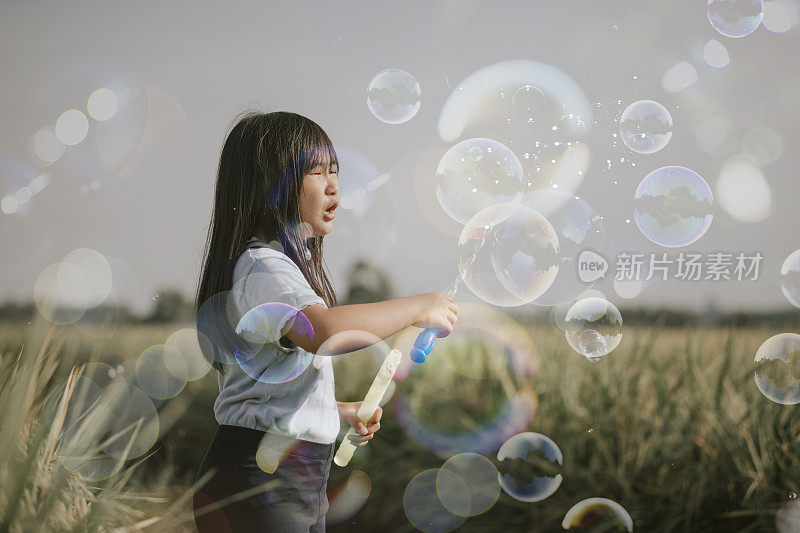 一个亚洲中国年轻女孩在稻田吹泡泡一个有趣的周末早上