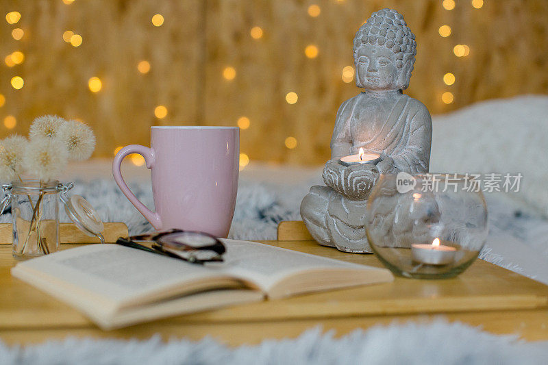 佛像与蜡烛和一本打开的书在前景-仙女灯在背景