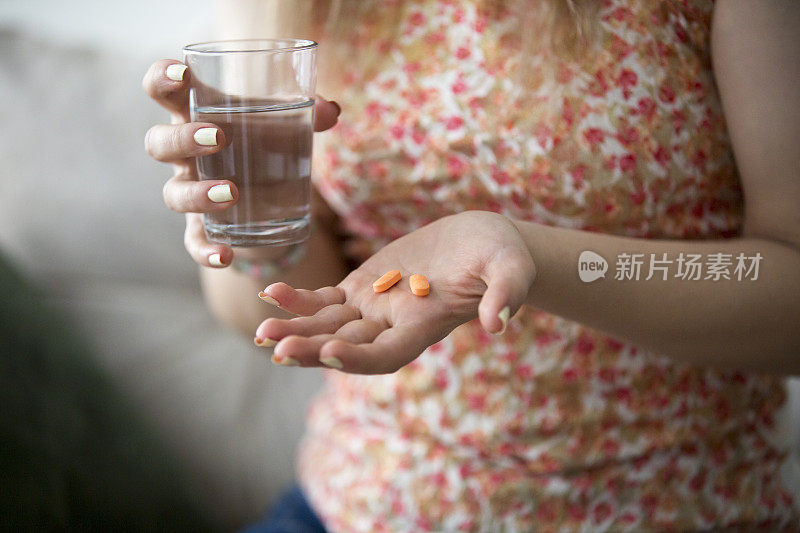 年轻女子拿着药和一杯水