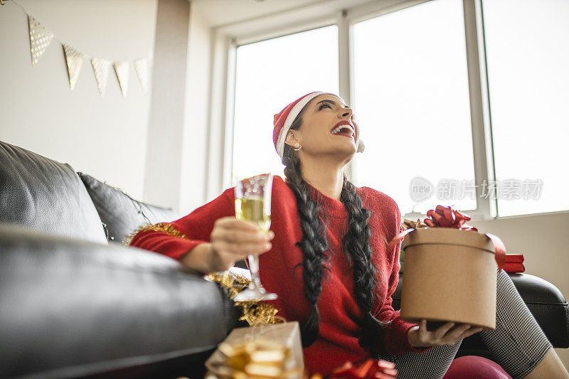 肖像的迷人微笑的女人喝香槟和打开她的圣诞或新年礼物