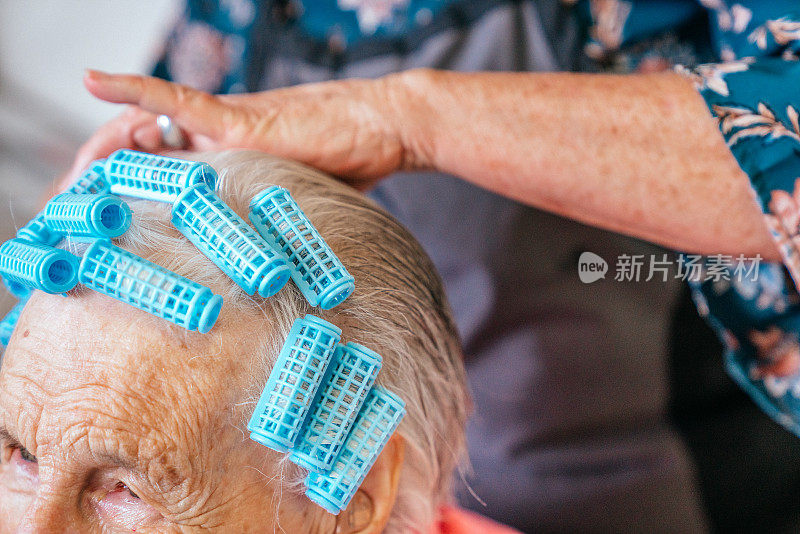 一个年长的白人妇女在家里烫发或用卷发器洗头的特写镜头