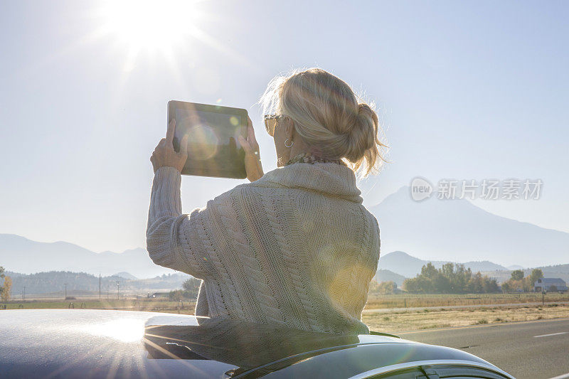 一名女子在汽车天窗用数码平板电脑拍照