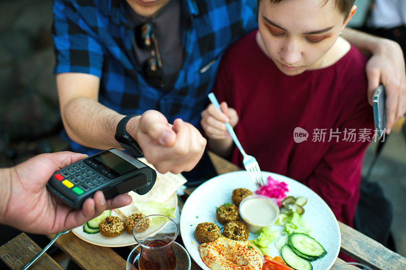 一对年轻夫妇在咖啡馆用智能手表付账