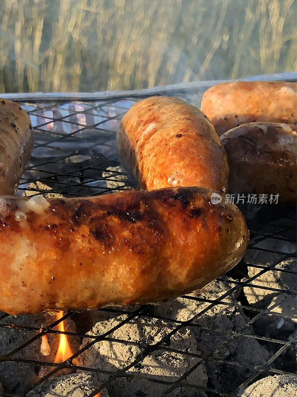 特写图像香肠烹饪一次性铝箔烧烤，聚焦前景