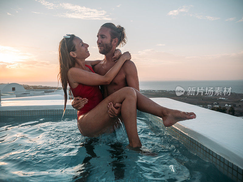 浪漫的情侣在热水浴缸里享受日落，男人抱着女朋友