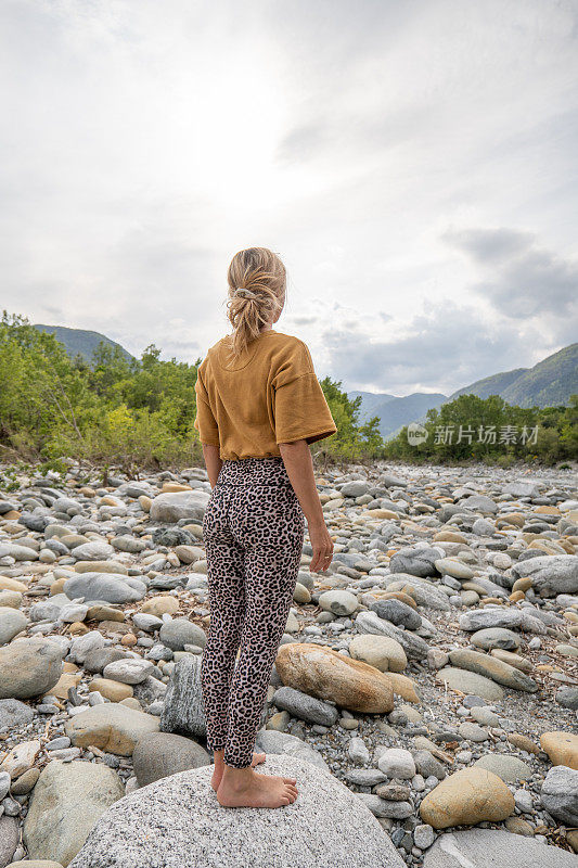 健康的女人凝视着岩石中的河流