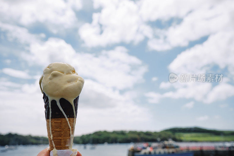 6月的一个阳光明媚的日子，康沃尔的圣莫斯，在水边手里拿着一个冰淇淋蛋筒。