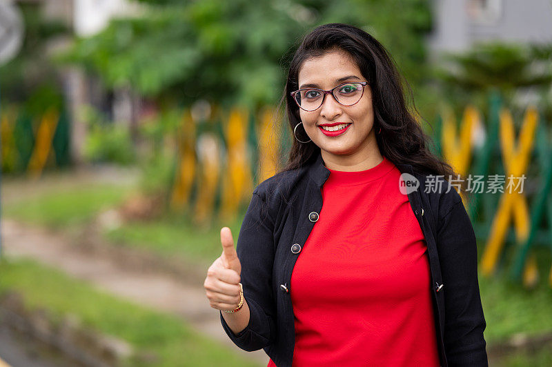 快乐自信的印度女学生看着镜头，在街上竖起大拇指。