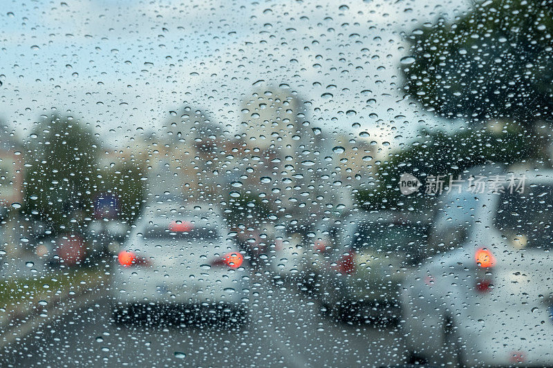 雨滴落在玻璃上。汽车交通红色刹车灯的背景