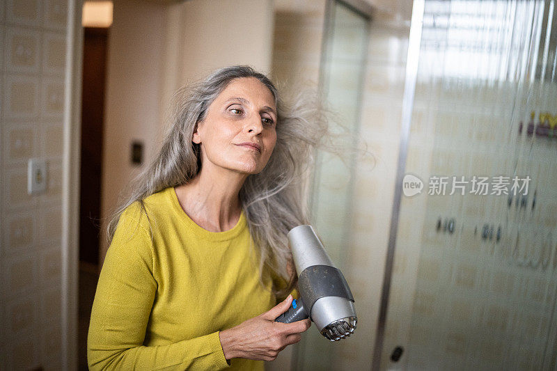 成熟的女人在家吹干头发