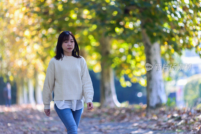 年轻女子喜欢在秋天的公园散步