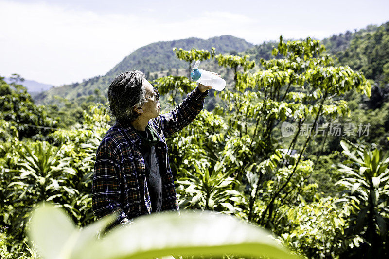 肖像高级成人在丛林徒步旅行期间喝淡水