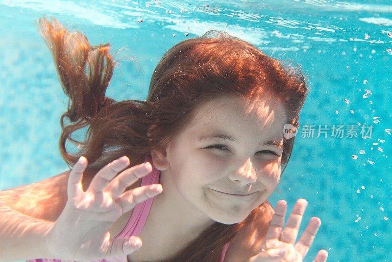 小女孩微笑着在水下游泳