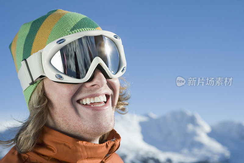 年轻的男性滑雪者戴着滑雪镜在山前