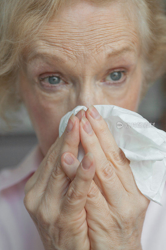 老妇人用纸巾擤鼻子