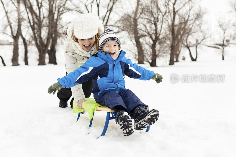 妈妈带着小男孩坐着雪橇下去了