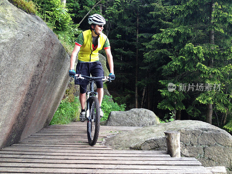 年轻的山地自行车手在森林里骑着山道下坡