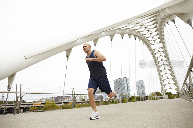 运动员穿着海军健身运动服在桥上跑步