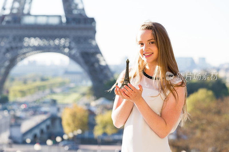 美丽的女孩拿着埃菲尔铁塔纪念品在巴黎