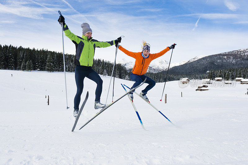 年轻夫妇在越野滑雪后跳跃