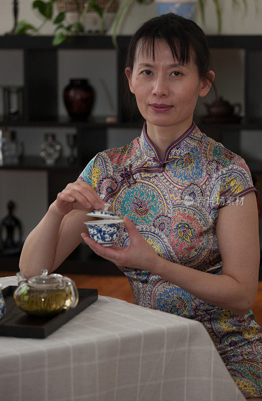 中国妇女穿着旗袍，拿着一个瓷茶杯