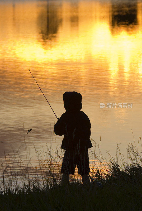 男孩在日落钓鱼