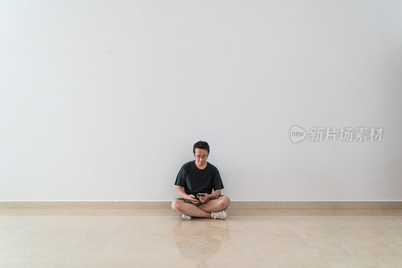 一个男人坐在地板上玩手机