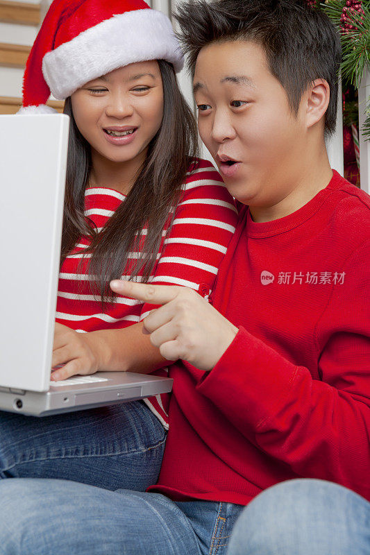 一对兴奋的亚洲夫妇指着笔记本电脑