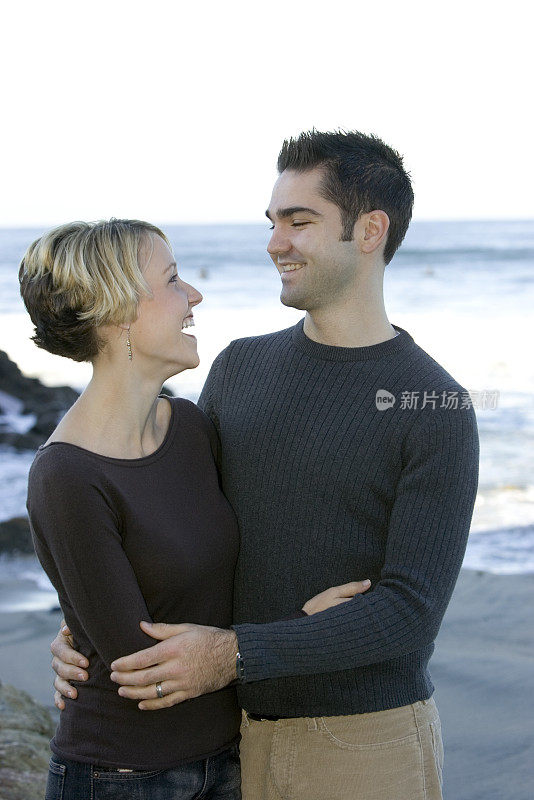 在海滩上大笑的年轻夫妇