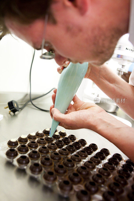 厨师在制作松露之前先将奶油放入巧克力模具中