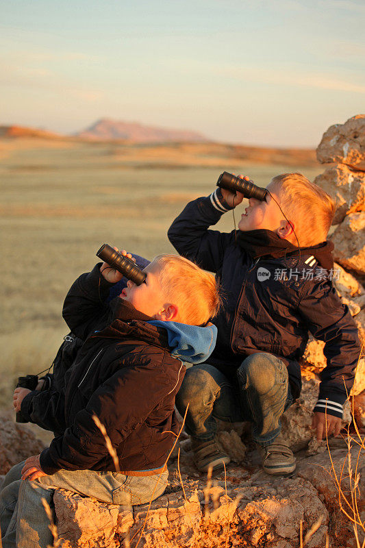 在非洲纳米比亚的日落游猎中，孩子们用双筒望远镜观看