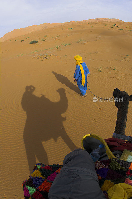 一个牧民在撒哈拉沙漠牵着一只骆驼