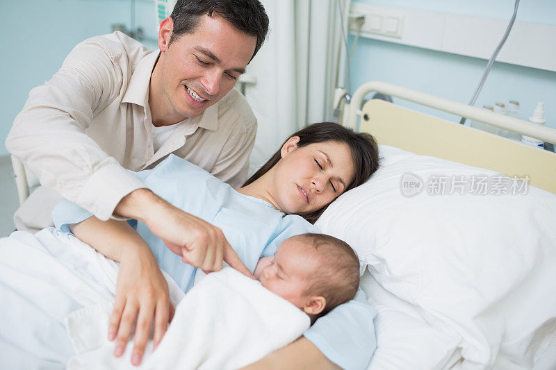 父亲看着熟睡的妻子和刚出生的婴儿