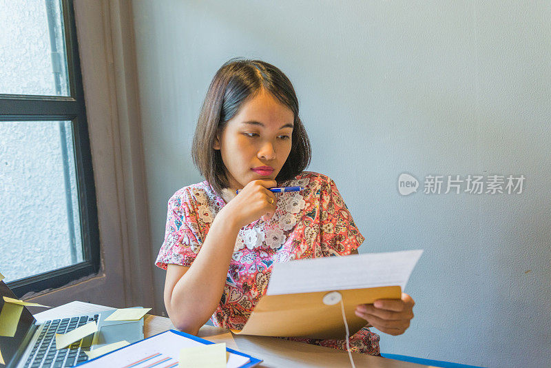 年轻的亚洲女商人拿着和阅读文件仔细