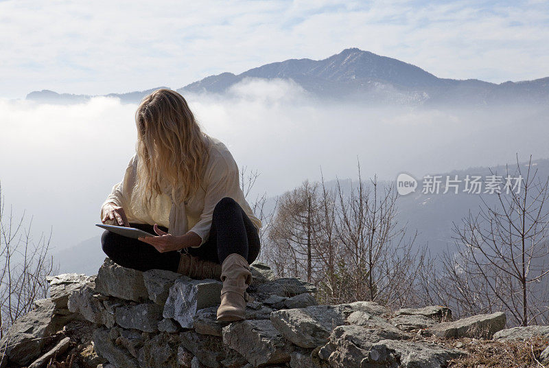 女人在山脊上使用数码平板电脑