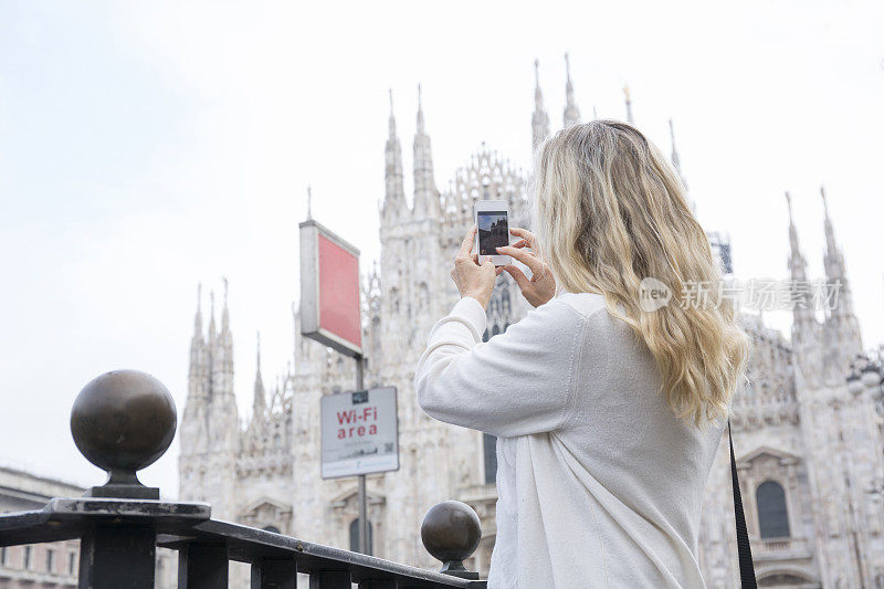 一名女子用智能手机为米兰大教堂拍照
