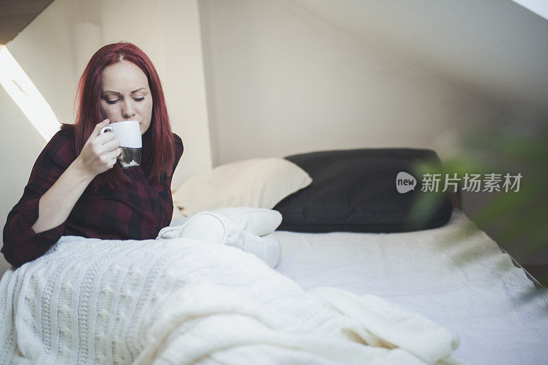 年轻女子在床上悠闲地喝着茶