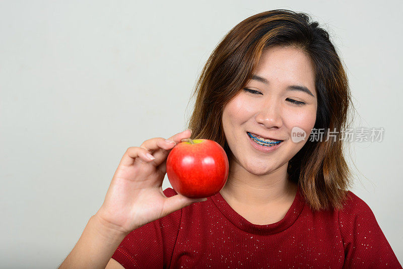 年轻的亚洲妇女穿着红色衬衫连衣裙，以白色的背景