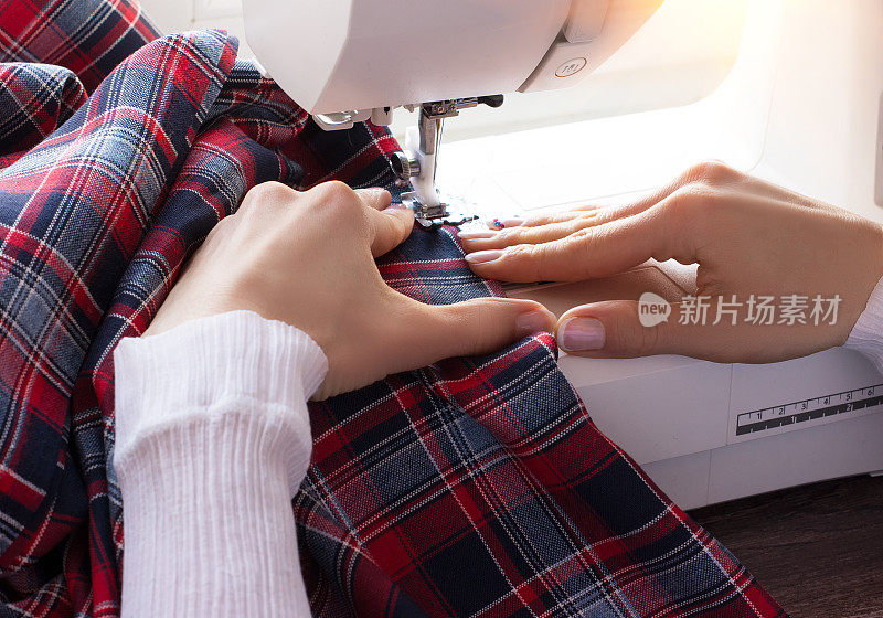 在缝纫机上缝制彩色织物的过程中，妇女的双手合拢。定制的环境。缝纫业务概念