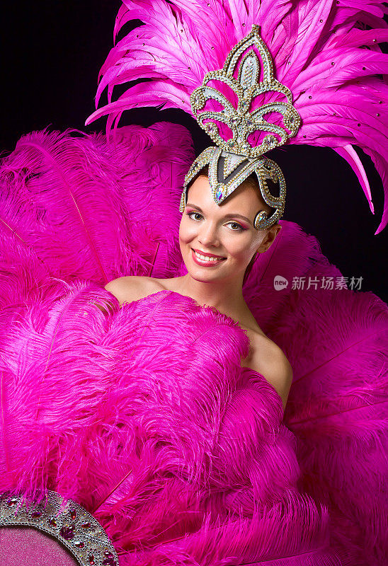 美丽的女孩穿着狂欢节的服装和粉红色的羽毛。