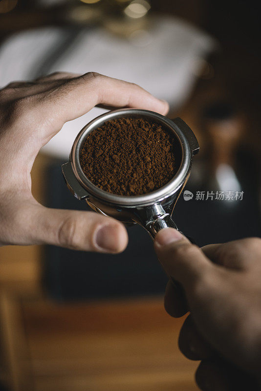 一步一步的煮咖啡的过程。男子正在进行咖啡梳理，夯实咖啡地面之前。