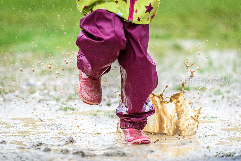 孩子们穿着胶靴和雨衣在水坑里跳来跳去。