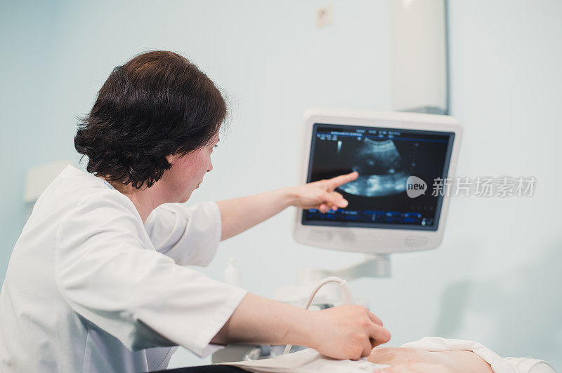 医生在电脑上向孕妇展示婴儿超声波图像