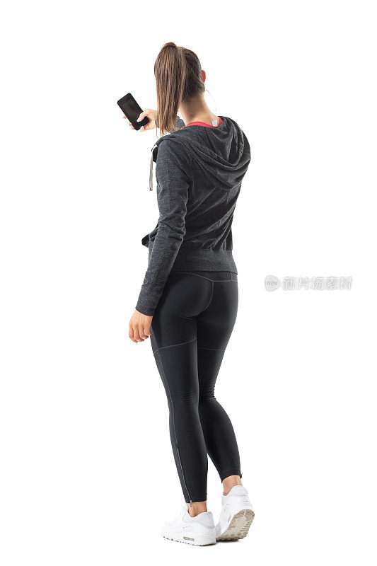 年轻的运动健康的女人用智能手机拍照的背影。