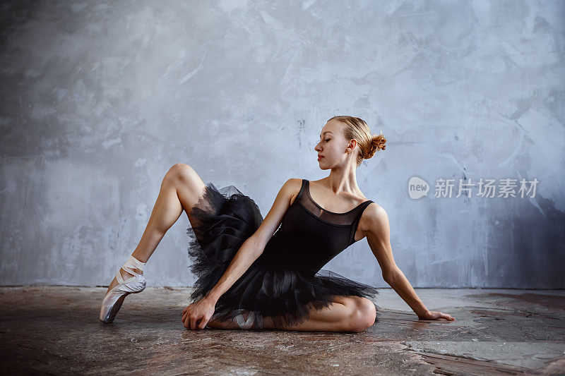 年轻的芭蕾舞女演员穿着黑色舞蹈服在阁楼工作室摆姿势