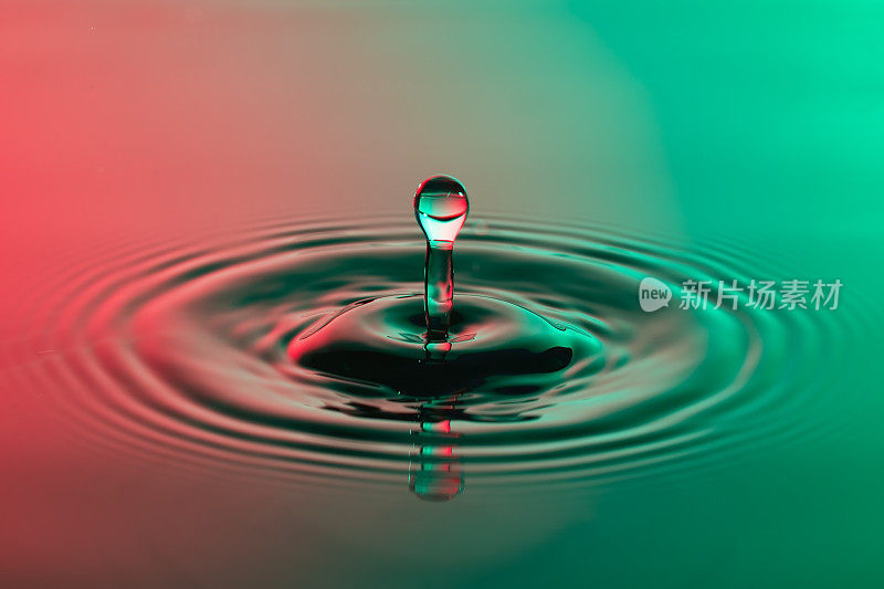 水滴近距离与同心涟漪在五颜六色的红色和绿色表面
