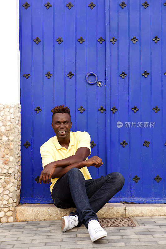 英俊的年轻非洲男子坐在外面微笑